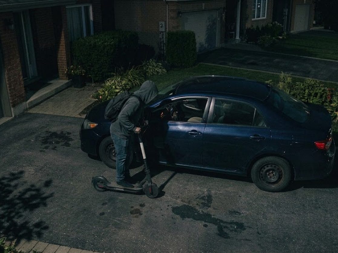A person at a car door on a driveway at night